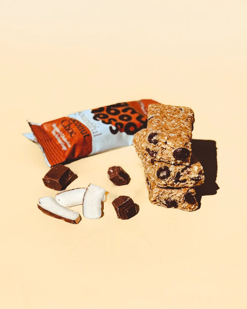Bountiful Coconut Choc snack bar with its wrapper, toasted coconut strips, and chocolate chunks
