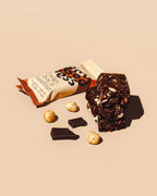 Fudgy Choc n' Hazelnut snack bar with its wrapper, whole hazelnuts, and dark chocolate chunks